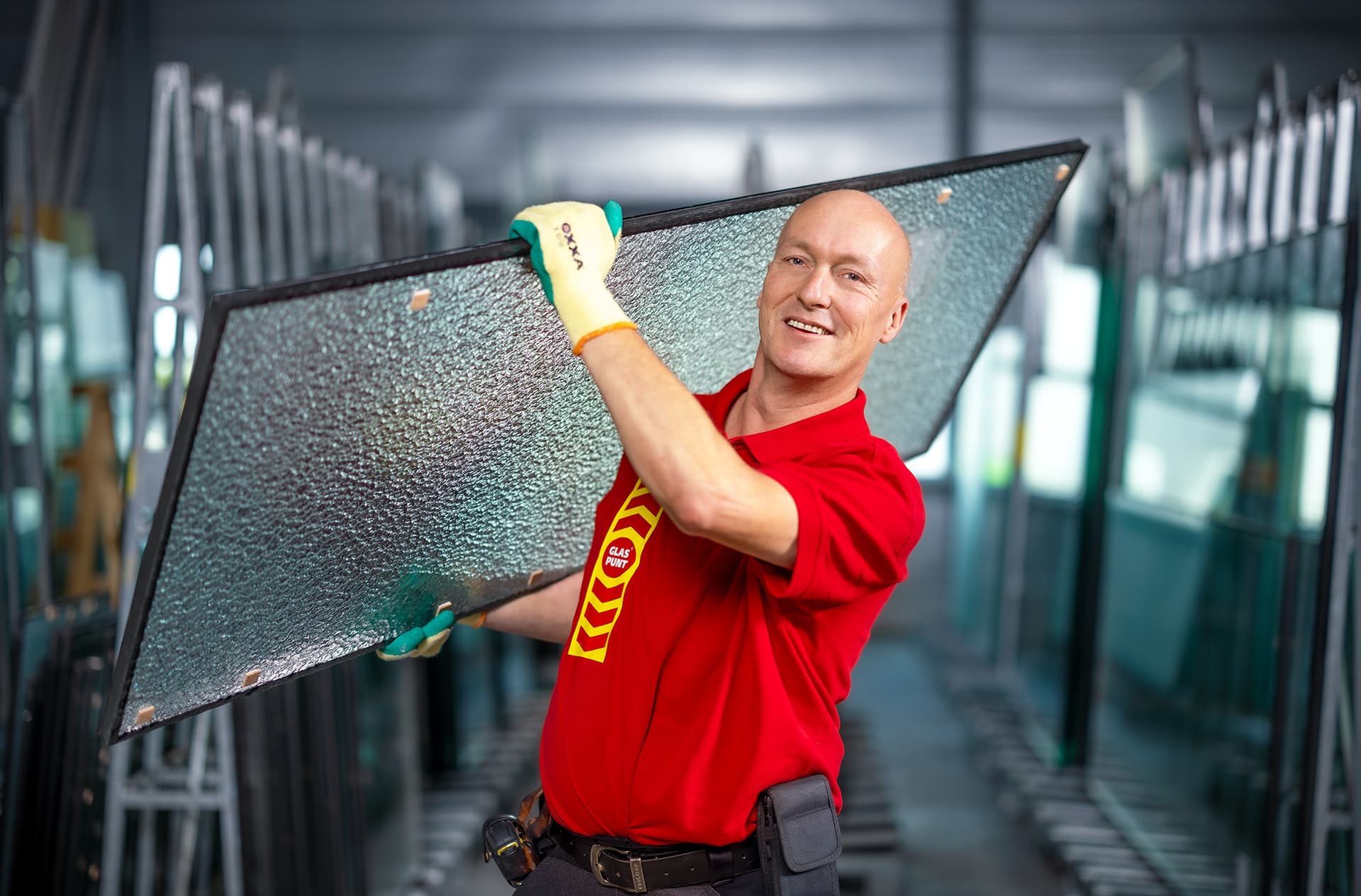 Glaszetter draagt een glasplaat in een opslagruimte.