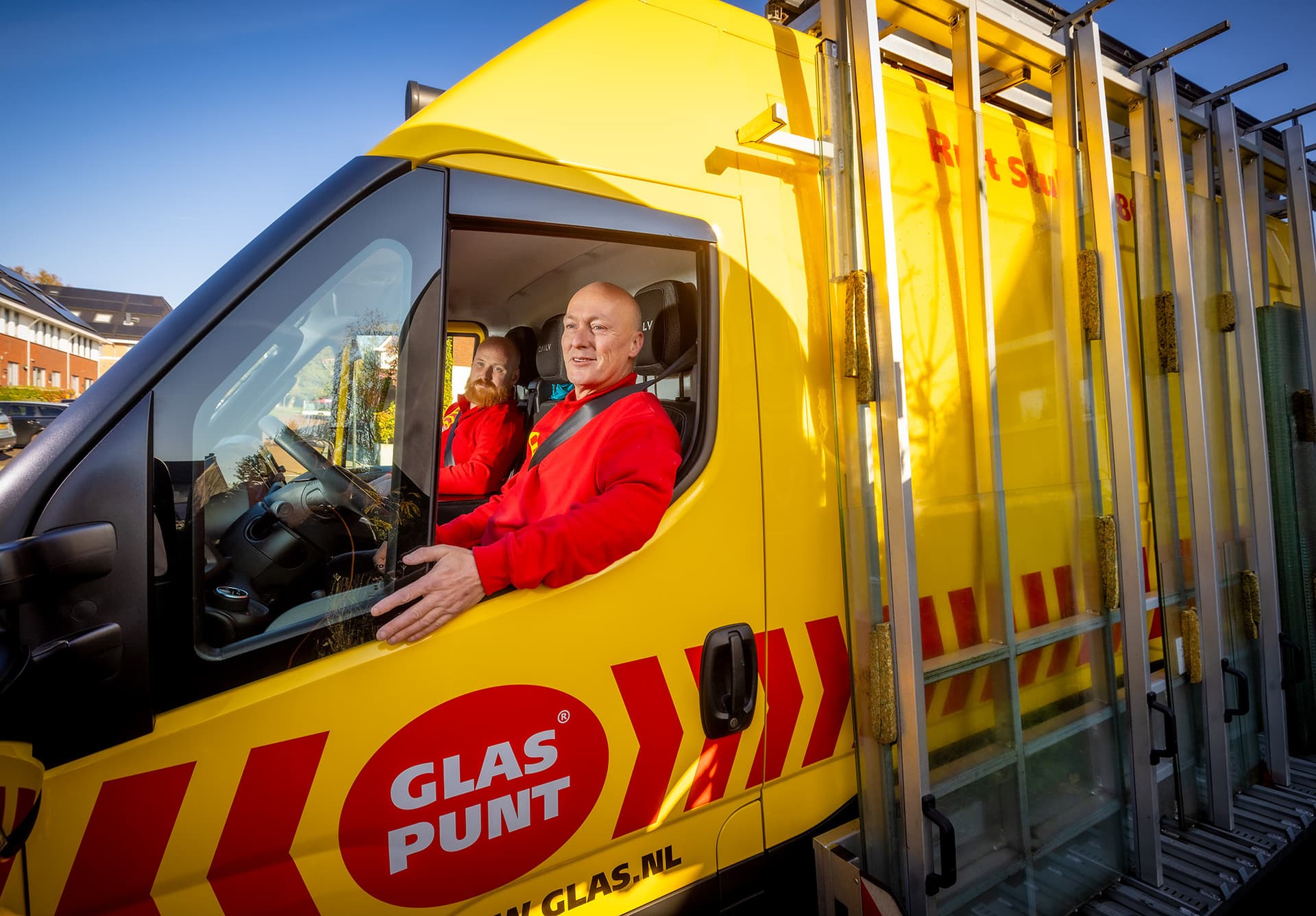 Glaszetter zit achter het stuur van een bedrijfsbus.