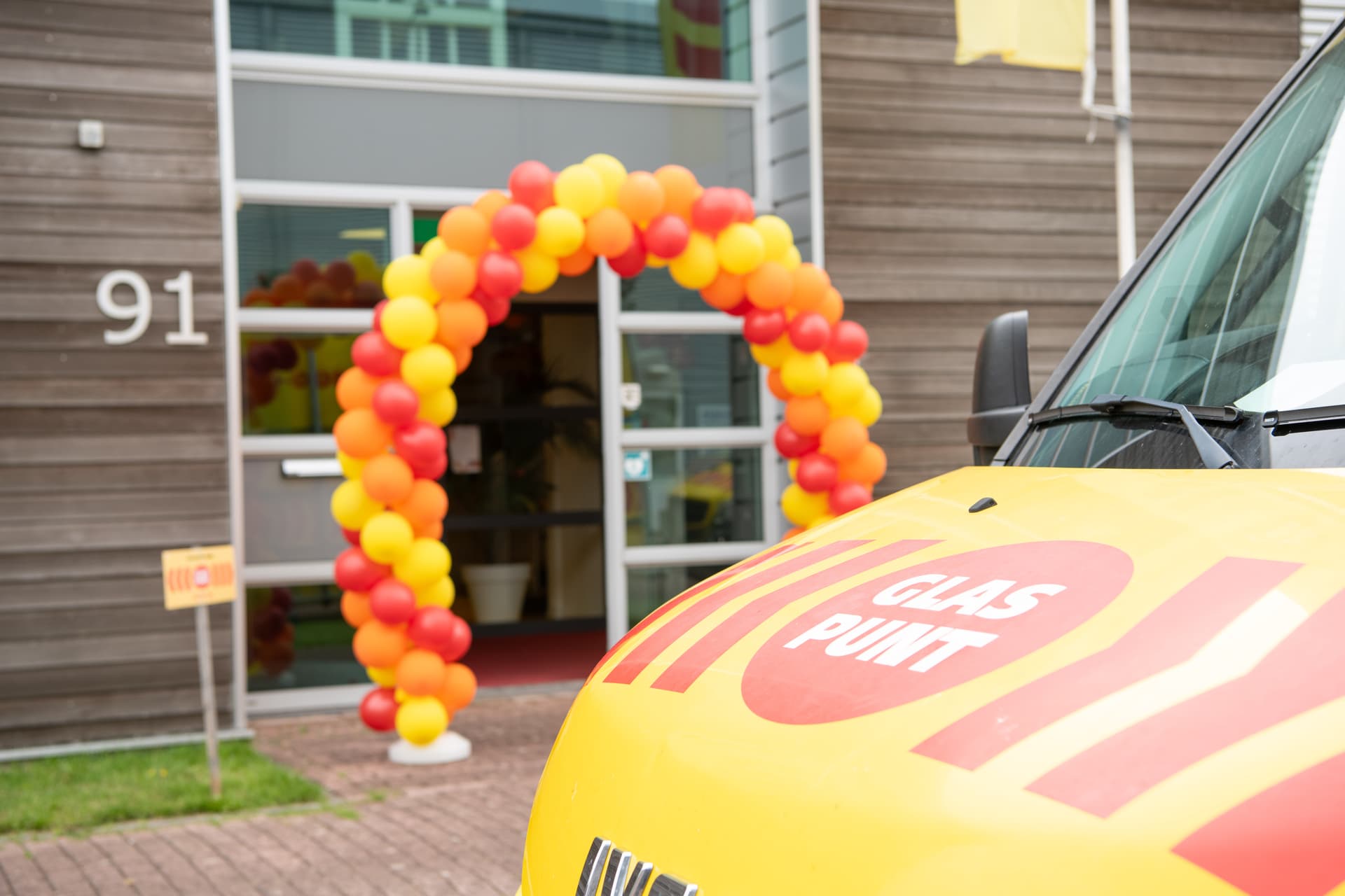 Kantoor pand met bus en ballonnen boog bij de deur