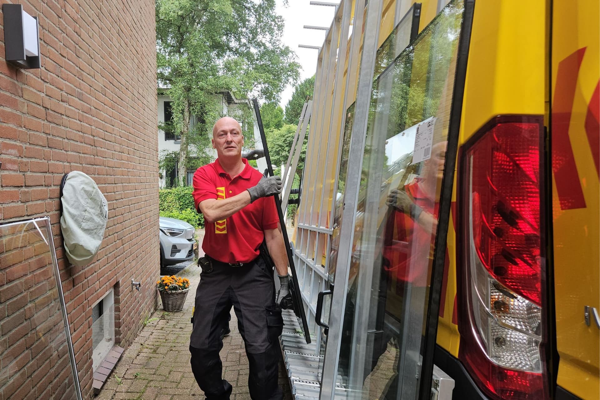 Glaszetter brengt glas van de glasbus naar de plaats waar deze wordt gemonteerd.