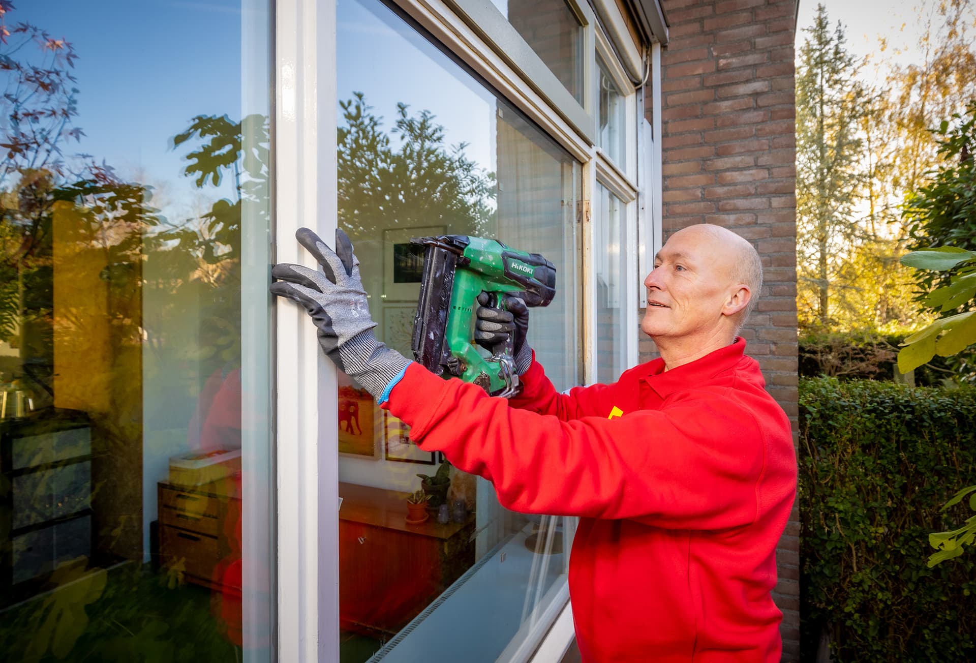 Glaszetter plaatst glaslatten rond een raam.