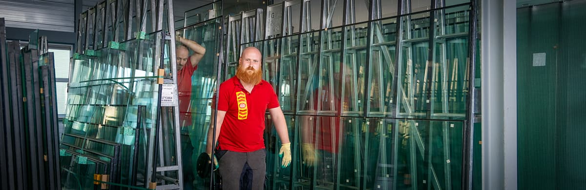 Twee glaszetters verplaatsen dubbel glas in de loods.
