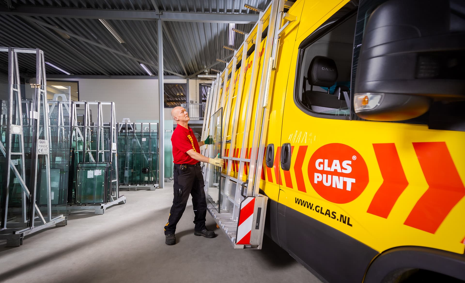 Monteur tilt een glasplaat op de bus voor transport.